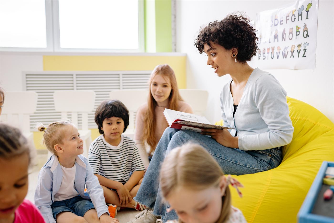 Docente leyendo un libro junto a estudiantes